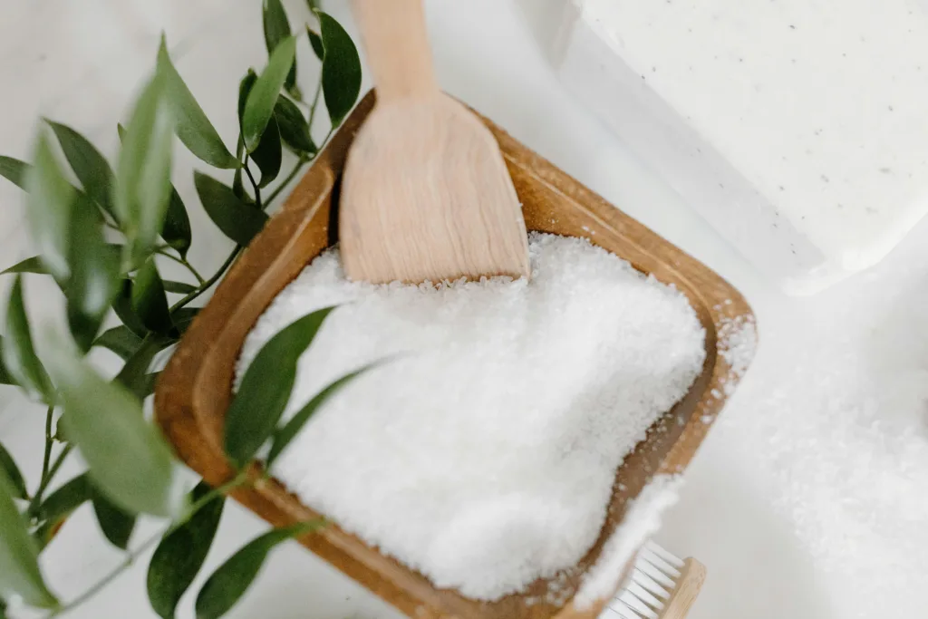 Close-up of bath salts, wooden spoon, and natural elements for a spa setting.